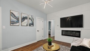 A modern living room with a fireplace, a flat-screen TV, and abstract wall art. - Luxury 5Bed 2Bath Apt w/Parking (Chicago)