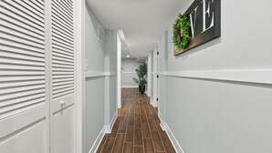 A hallway with white walls, a wooden floor, and a sign with the word "LOVE" on the right wall. - Luxury 5Bed 2Bath Apt w/Parking (Chicago)