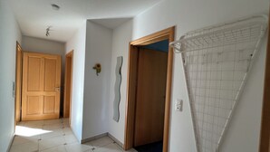 A hallway with wooden doors, a wall-mounted mirror, and a ceiling light fixture.
