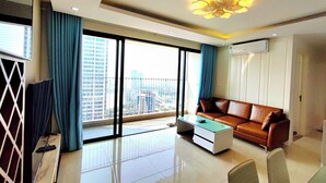 A modern living room with a sofa, a coffee table, and a large window with curtains.