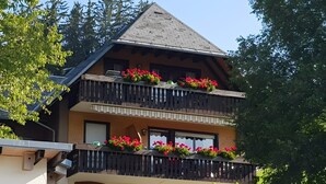 Un edifici de diversos pisos amb balcons, un rètol que diu 'LORENZENHAUSLE' i una petita zona d'estar a l'exterior.