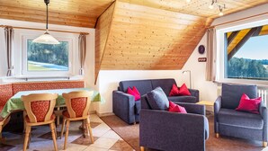 Una stanza accogliente con soffitto in legno, un'area pranzo con tavolo e sedie, e un divano.