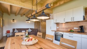 Una cocina moderna con vigas de madera, armarios blancos y una mesa de comedor con fruta.