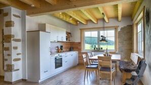 Una cocina moderna con armarios blancos, un comedor con sillas de madera y una pared de acento de piedra.