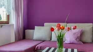 A room with a bed, a window with curtains, a vase with flowers, and a striped table. - Apartment 'Säntis, 50qm' with Balcony and Wi-Fi (Mühlingen)