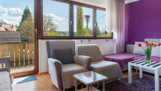 A room with two armchairs, a small table, a sofa, and a view through large windows. - Apartment 'Säntis, 50qm' with Balcony and Wi-Fi (Mühlingen)