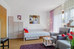 A bedroom with a bed, a chair, a small table, a wardrobe, and a painting on the wall. - Apartment 'Säntis, 50qm' with Balcony and Wi-Fi (Mühlingen)
