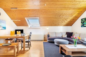A modern loft with a sloped ceiling, a dining area with wooden furniture, a sofa set, and a painting on the wall. - Apartment 'Bodensee, 85qm' with Private Terrace and Wi-Fi (Mühlingen)