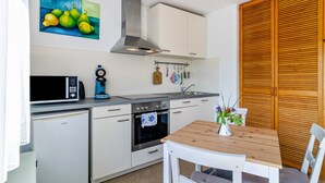 A compact kitchen with a microwave, toaster, oven, and a wooden table with a vase of flowers.