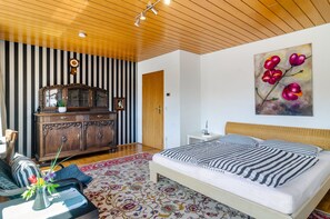 Un dormitorio con una cama, un tocador, un reloj y un cuadro.