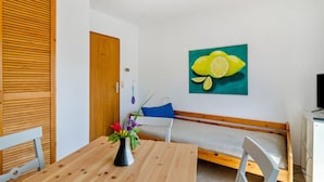 A room with a wooden table, a bench, a wall-mounted painting of lemons, and a door.