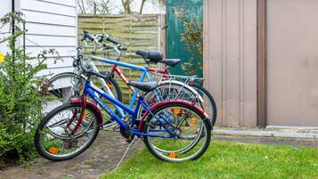 En cykel parkeret ved et hus med et træhegn og et skur i baggrunden.