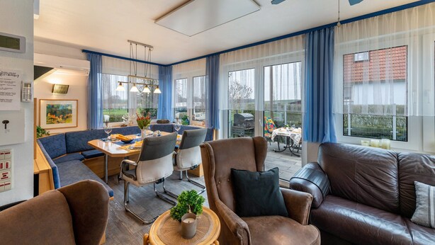 Quarto de hotel moderno com área de refeições, sofá e ventoinha no teto.