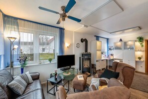 A living room with a television, sofa, ottoman, and a fireplace.