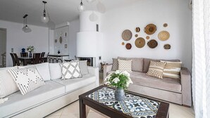 Una sala de estar moderna con un sofá gris, una mesa de centro con tapa estampada y una pared decorada con cestas tejidas.