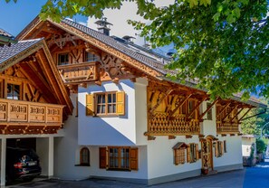 A traditional wooden house with a balcony, a garage, and a small garden area. - Apartment 'Wiagsog' with Mountain View, Balcony and Wi-Fi (Garmisch-Partenkirchen)