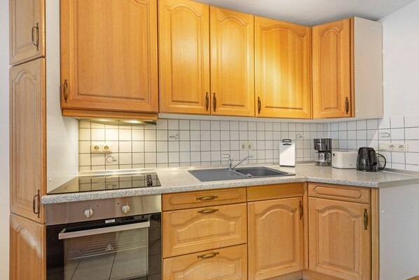 A kitchen with wooden cabinets, a stainless steel oven, a sink, and a coffee maker.