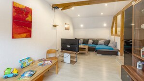 A living room with a TV, wooden beams, a sofa, and a bookshelf. - Apartment 'Sonnenblume' with Balcony and Wi-Fi (Lichtenfels)