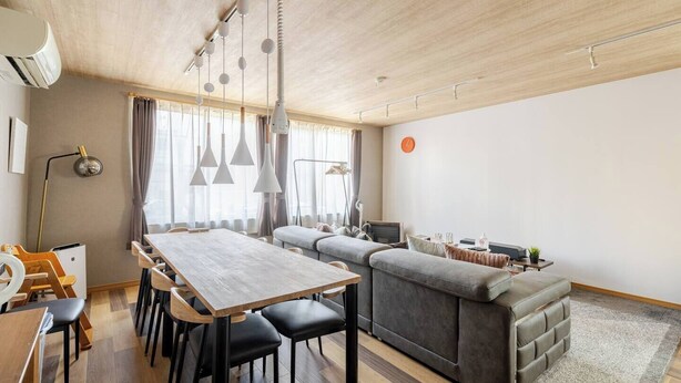 Una sala de estar moderna con comedor, sofá gris y televisor.