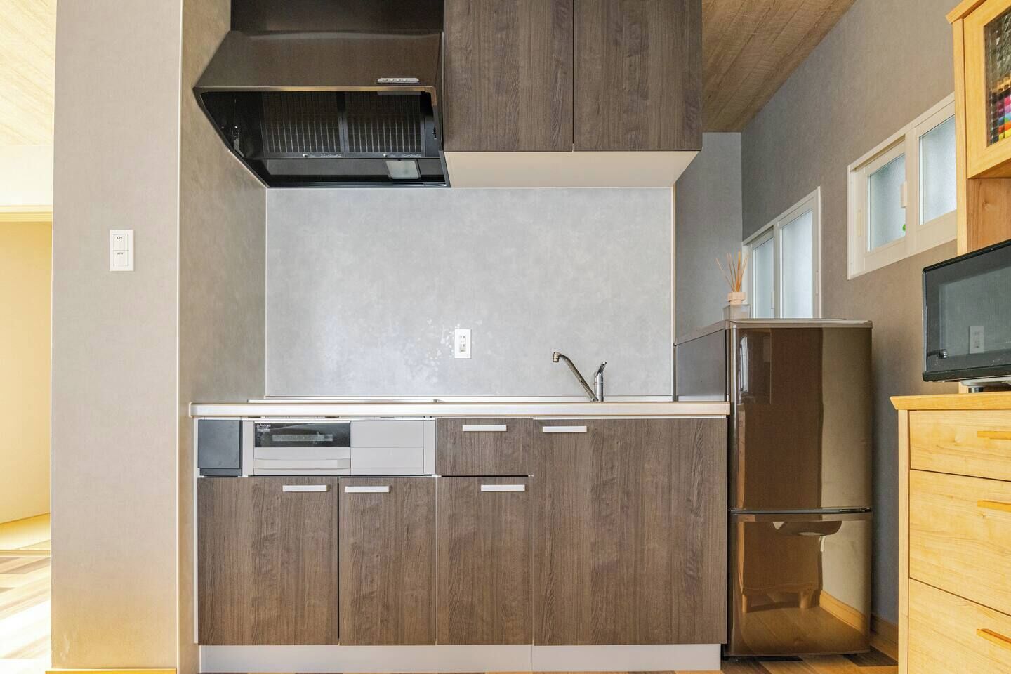 A modern kitchen with wood cabinets, a stainless steel sink, and a built-in dishwasher.
