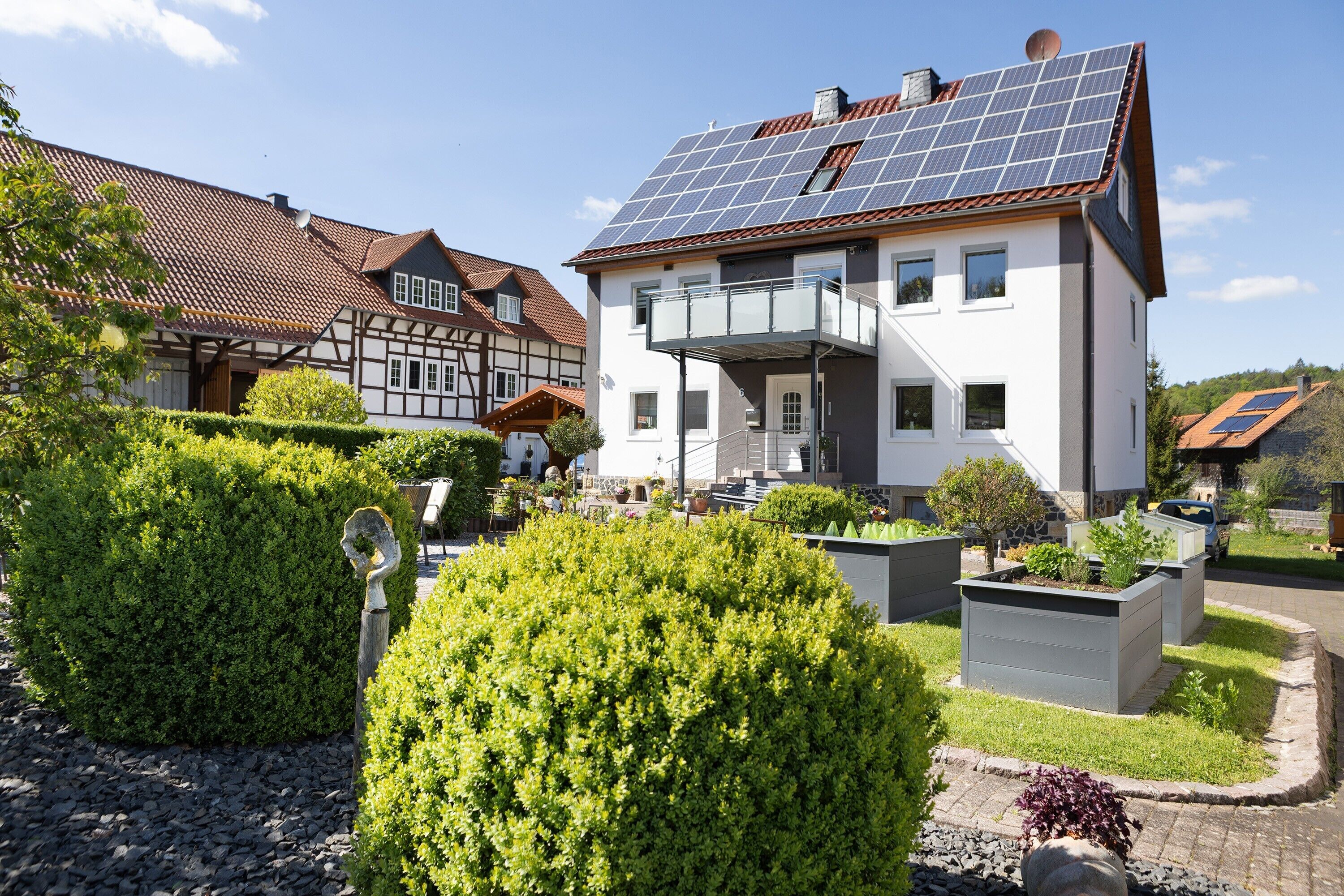 Ein modernes Haus mit Solaranlage, einem Balkon und gepflegten Gärten.