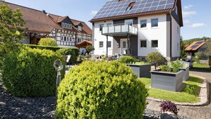 Une maison moderne dotée de panneaux solaires, d’un balcon et de jardins bien entretenus.
