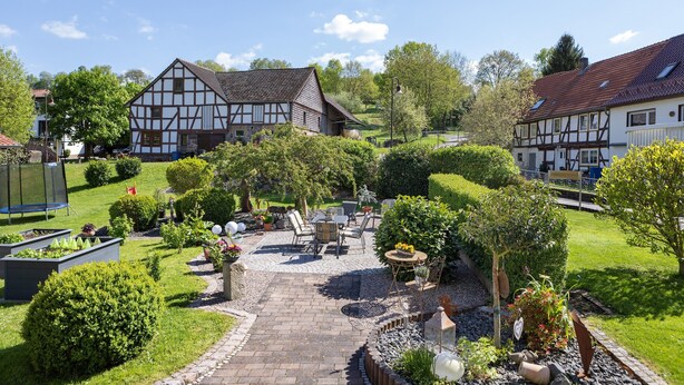 Une cour avec un chemin pavé, un espace aménagé pour s’asseoir et des maisons traditionnelles à colombages.