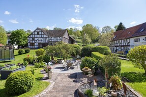 Een binnenplaats met een verhard pad, een zitgedeelte en traditionele vakwerkhuizen.