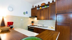 Een keuken met houten kastjes, een fornuis en een spoelbak.