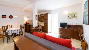 Een moderne woonkamer met een bank, eettafel en keukenhoek.