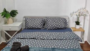 A neatly arranged bedroom with a bed, pillows, a nightstand, a small table, and a wall-mounted painting. - 15 mins to Airport|Gateway to NSW (Campbellfield)