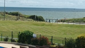 A grassy area with a view of the sea, a fence, and a sign indicating a walking path. - Large 2-bedroom apartment with sea and pool views. Beach 40 meters away. (damgan)