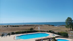 A pool area with clear blue water, surrounded by a fenced area with a view of the sea. - Large 2-bedroom apartment with sea and pool views. Beach 40 meters away. (damgan)
