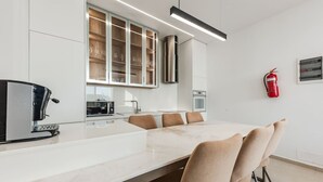 Une cuisine moderne équipée d’un four à micro-ondes encastré, d’une machine à café et d’un meuble vitré.