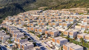 Un quartier résidentiel moderne, composé d’immeubles d’appartements aux façades uniformes, disposés selon un plan en damier et entouré de montagnes.