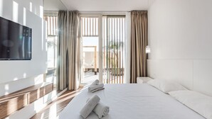 Une chambre d’hôtel moderne avec un grand lit, un téléviseur à écran plat fixé au mur et une vue sur l’extérieur par la fenêtre.
