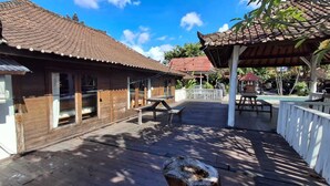 Ein Holzhaus mit Ziegeldach, einer Holzterrasse und einer überdachten Sitzgelegenheit.