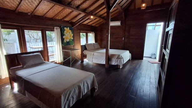 Ein Zimmer mit zwei Betten, einer Holzbalkendecke und einem großen Fenster.