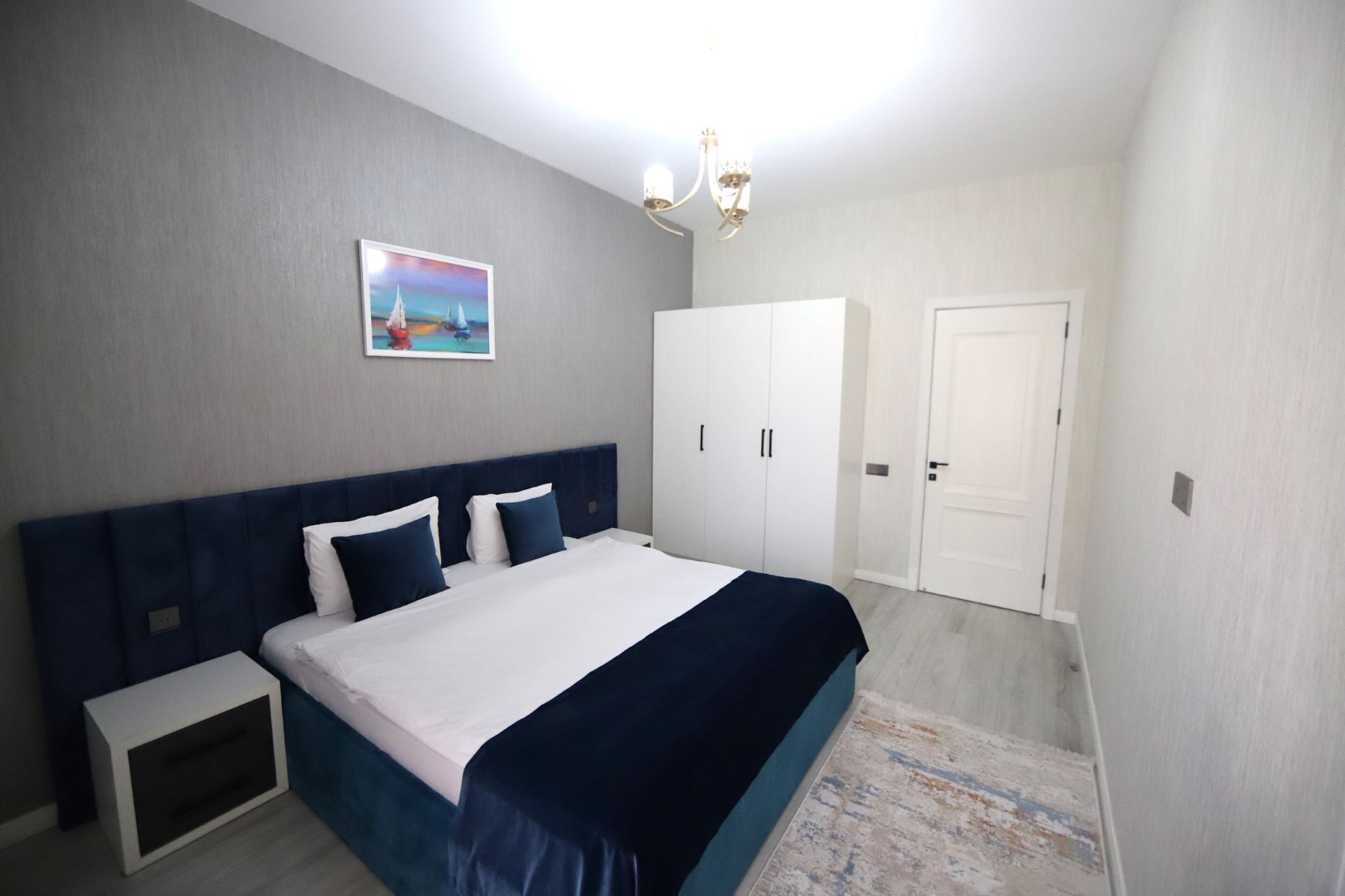 Une chambre à coucher avec un lit, une table de chevet, une armoire et une porte.