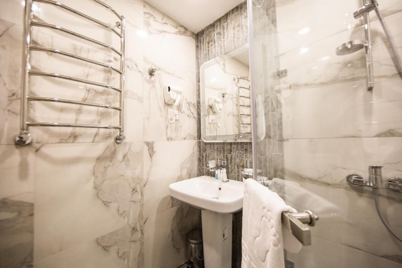 Een badkamer met een marmeren wastafel, een handdoekhouder, een spiegel en een douche.