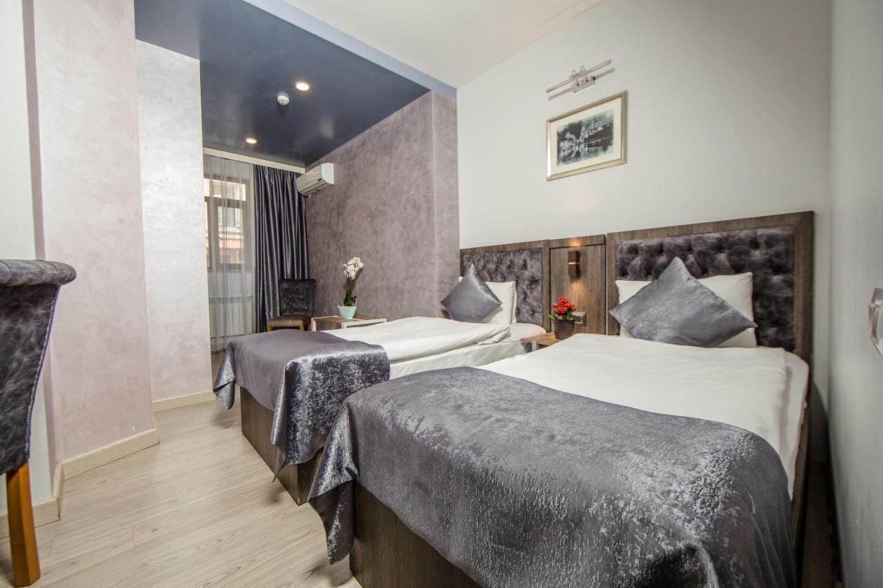 Une chambre d’hôtel avec deux lits, une grande fenêtre et un tableau au mur.