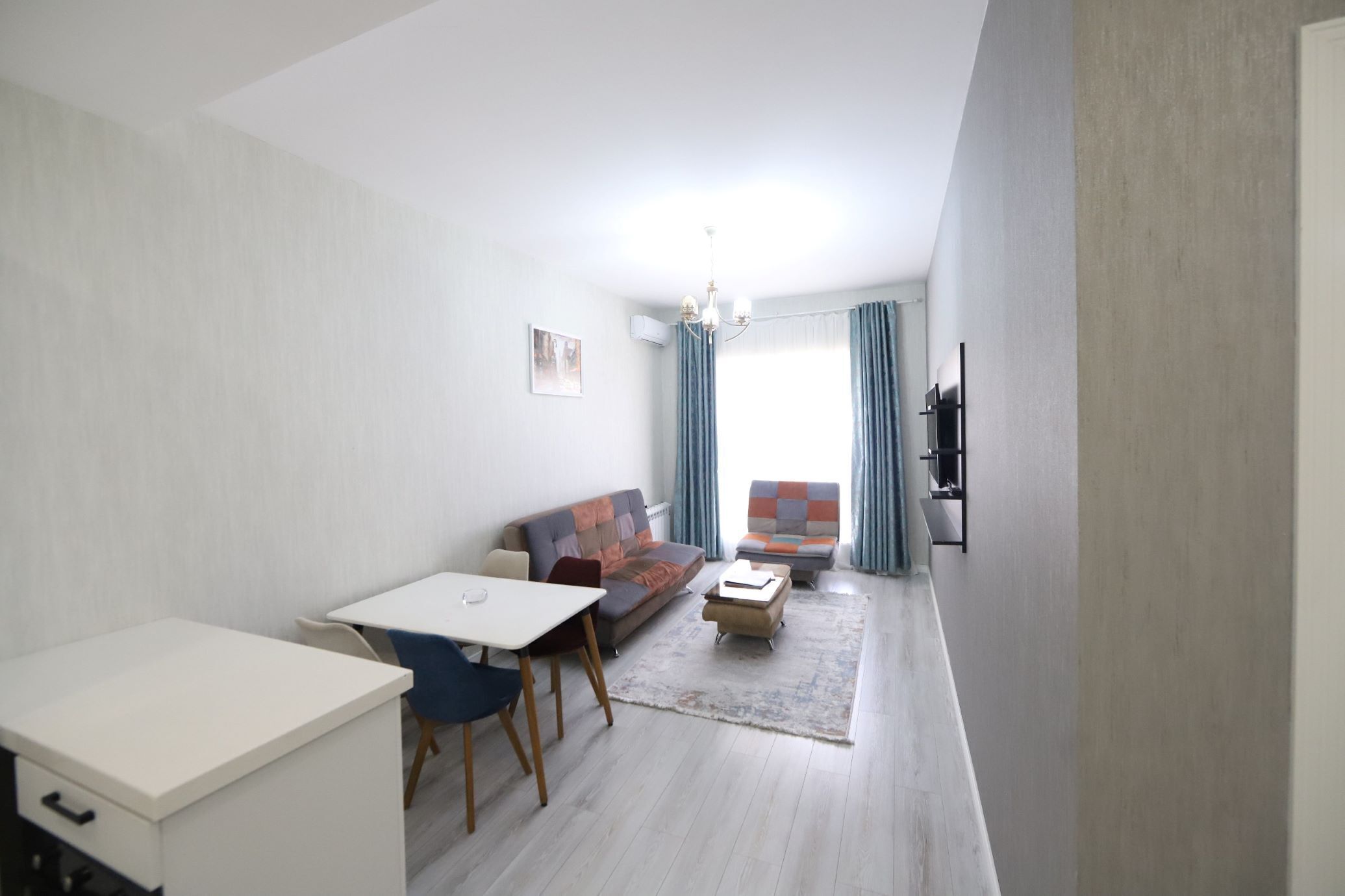 A modern living room with a sofa, a dining table, and a small coffee table.