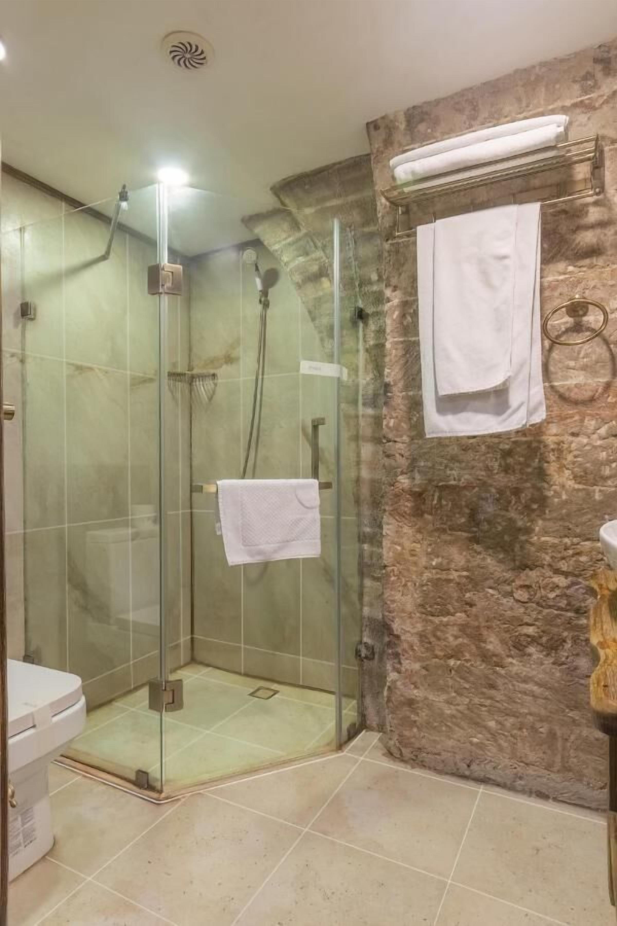 Ducha con cerramiento de vidrio y una toalla blanca colgada en la pared.