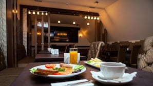 Un comedor con una mesa preparada para el desayuno, incluyendo platos de comida, un vaso de zumo de naranja y una taza de café.