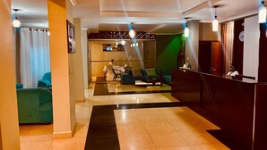 Een hotel lobby met een receptiebalie, zithoek met banken en een incheckbalie.