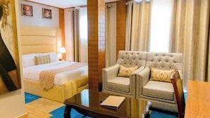 Een hotelkamer met een bed, een slaapbank, een salontafel en gordijnen.