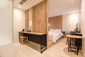 A modern hotel room with a wooden slatted wall, a bed, a desk with a chair, and a small table with a chair. - Hwagokhoteln (Seoul)