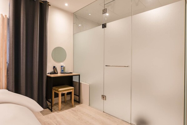 A modern bedroom with a bed, a small wooden stool, a mirror, and a wardrobe. - Hwagokhoteln (Seoul)