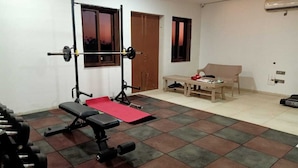 Un gimnasio en casa con una estructura para sentadillas, banco y discos de pesas.