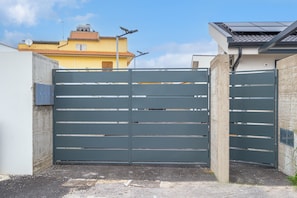 Une entrée fermée par un portail, avec un mur en béton et un portail métallique.